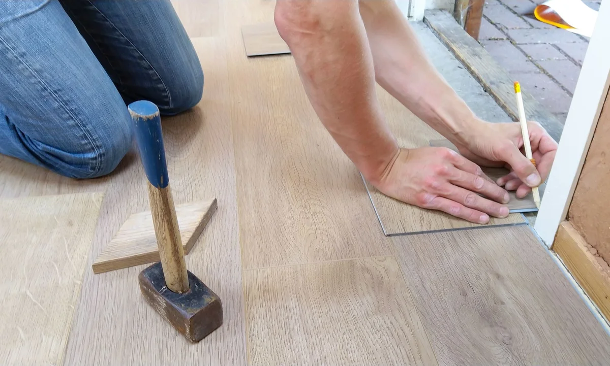 Hand markiert eine Holzplatte für den Bodenzuschnitt